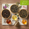 Bio-Darjeeling Tee: Teeblätter in Holzschalen und Tassen mit aufgebrühtem Tee