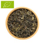 Eine Holzschale, gefüllt mit getrockneten, biologischen Darjeeling Grünteeblättern