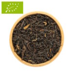 eine Holzschale die mit getrockneten, dunklen, lose Bio-Schwarzteeblättern der Sorte Assam Chardwar gefüllt ist.