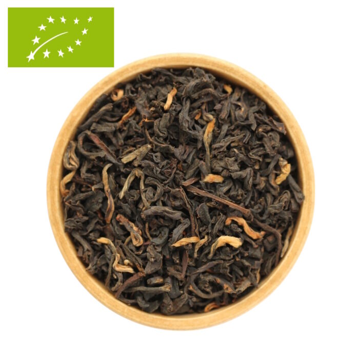 eine Holzschale die mit getrockneten und gerollten Bio-Schwarzteeblättern der Sorte Assam Tonganagaon gefüllt ist.