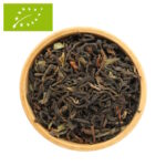 Eine Draufsicht auf eine Holzschale, die mit einem Bio Tee Bengalischen Mischung gefüllt ist. Zu sehen ist ein grobes, loses Blatt aus dunklem Bio-Schwarztee, das mit grünen Akzenten Blattanteilen durchsetzt ist.