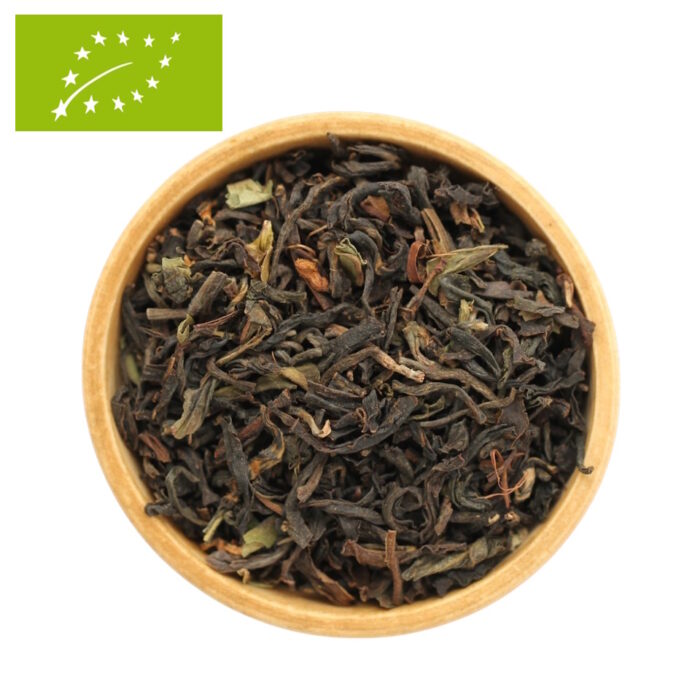 Eine Draufsicht auf eine Holzschale, die mit einem Bio Tee Bengalischen Mischung gefüllt ist. Zu sehen ist ein grobes, loses Blatt aus dunklem Bio-Schwarztee, das mit grünen Akzenten Blattanteilen durchsetzt ist.