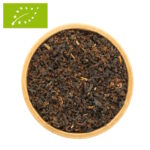 Eine Draufsicht auf eine Holzschale, gefüllt mit losem Bio-Schwarztee Golden Breakfast. Die dunklen Teeblätter sind gleichmäßig mit auffälligen, goldfarbenen Blattspitzen durchsetzt, die im Licht schimmern.