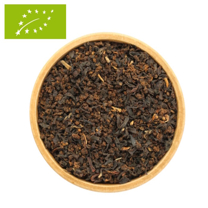 Eine Draufsicht auf eine Holzschale, gefüllt mit losem Bio-Schwarztee Golden Breakfast. Die dunklen Teeblätter sind gleichmäßig mit auffälligen, goldfarbenen Blattspitzen durchsetzt, die im Licht schimmern.