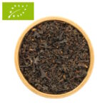 Eine Draufsicht auf eine kleine, Holzschale, die randvoll mit einer losen Bio-Ostfriesentee-Mischung gefüllt ist. Das Bild zeigt ein sehr feines, gleichmäßiges und tiefdunkles Blatt, das typisch für kräftige Assam-basierte Mischungen ist.