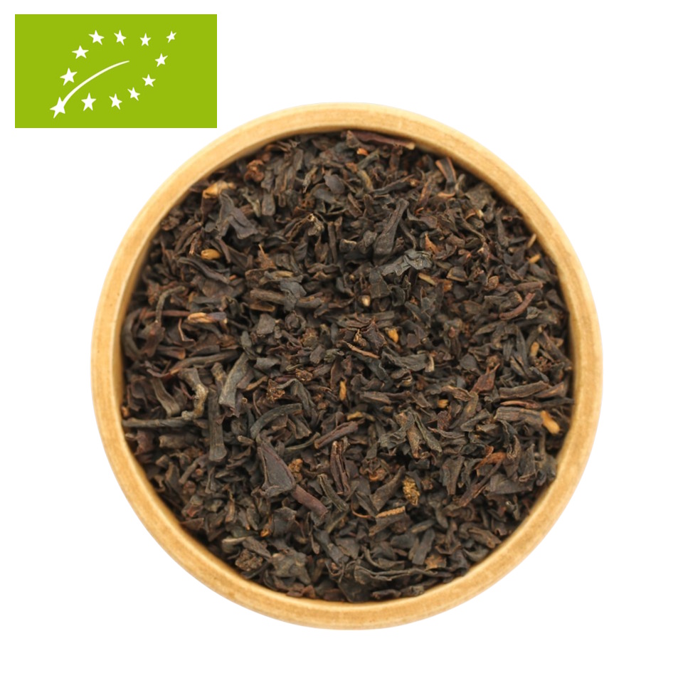 Eine Draufsicht auf eine kleine, Holzschale, die randvoll mit einer losen Bio-Ostfriesentee-Mischung gefüllt ist. Das Bild zeigt ein sehr feines, gleichmäßiges und tiefdunkles Blatt, das typisch für kräftige Assam-basierte Mischungen ist.